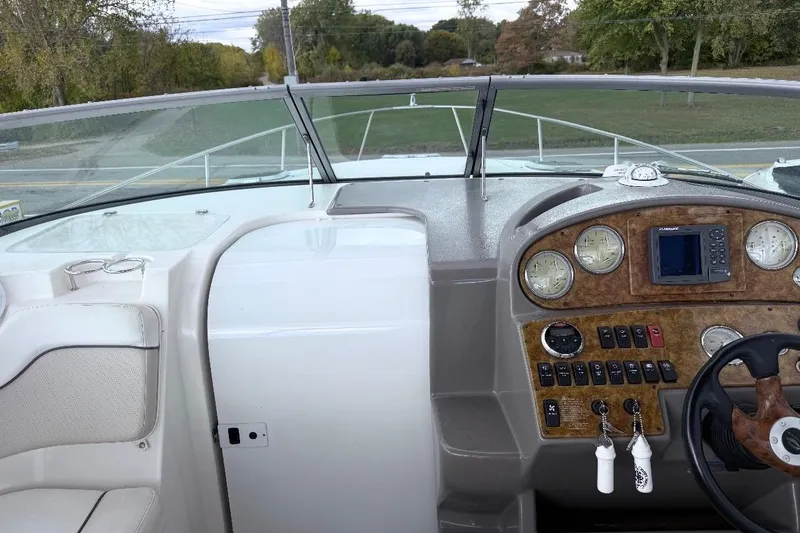 Slide: The Image of 2006 Rinker Fiesta Vee 300 boat dashboard with gauges and controls, surrounded by lush greenery. - 7