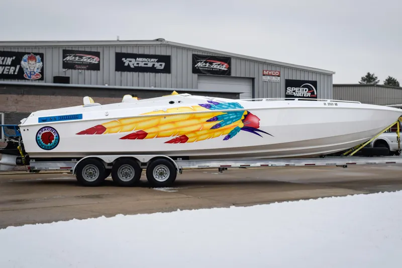 The Image of 1998 Apache 36 WARRIOR speedboat with vibrant feather artwork on trailer. - 0