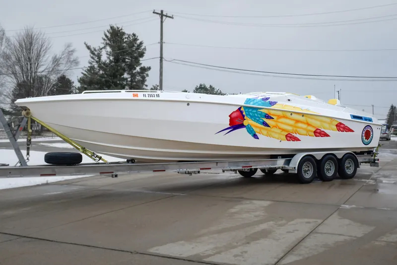 Slide: The Image of 1998 Apache 36 WARRIOR boat with vibrant feather design on trailer. - 6