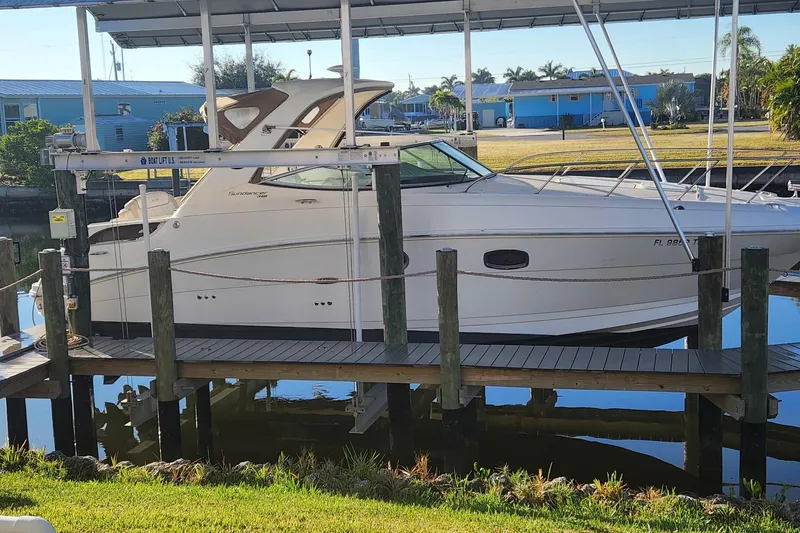 The Image of 2012 Sea Ray 310 Sundancer boat docked under a canopy on a sunny day. - 0