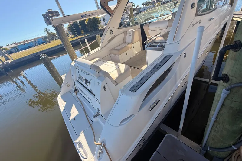 Slide: The Image of 2012 Sea Ray 310 Sundancer docked, showcasing sleek design and spacious seating area. - 101