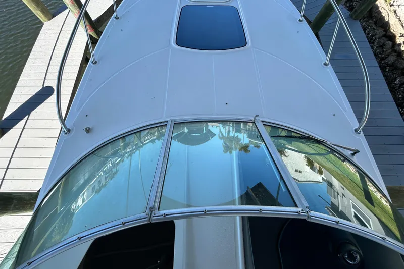 Slide: The Image of 2012 Sea Ray Sundancer 310 boat docked, showcasing sleek design and spacious seating area. - 118