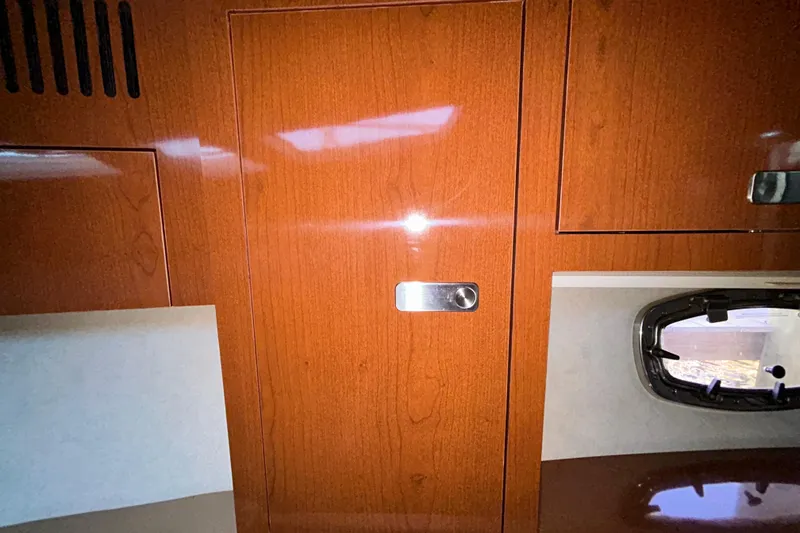 Slide: The Image of Interior of 2012 Sea Ray Sundancer 310, featuring seating and wooden cabinetry. - 175