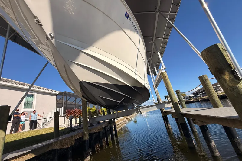 Slide: The Image of 2012 Sea Ray 310 Sundancer on lift at dockside, sunny day, waterfront view. - 19
