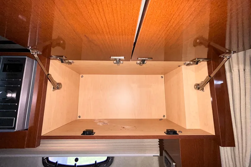 Slide: The Image of Interior cabin of 2012 Sea Ray Sundancer 310, featuring storage compartments and beige upholstery. - 190