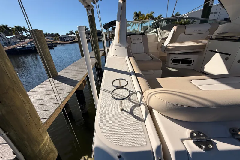 Slide: The Image of 2012 Sea Ray 310 Sundancer boat docked, featuring beige seating and cup holders. - 26