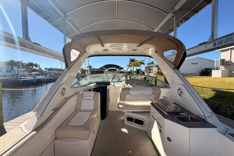 Slide: The Image of 2012 Sea Ray 310 Sundancer boat interior with seating and kitchenette, docked under a canopy. - 32