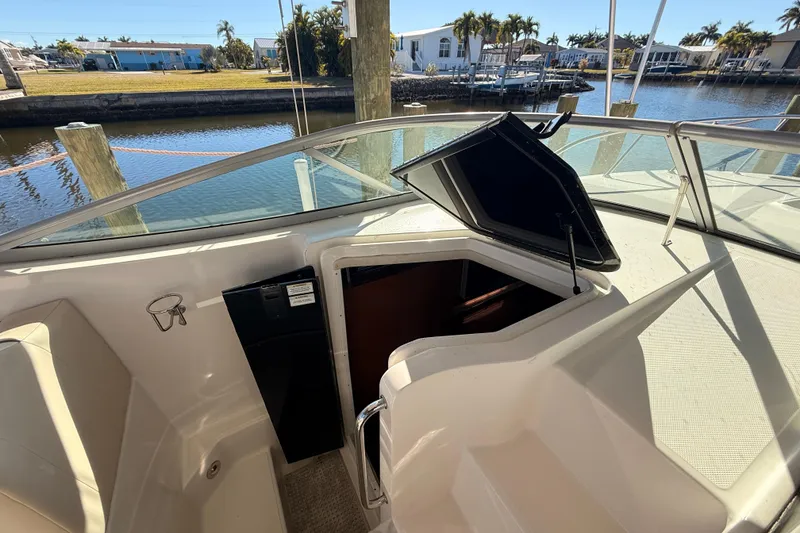 Slide: The Image of 2012 Sea Ray 310 Sundancer cabin entrance with open hatch, docked by waterfront. - 54