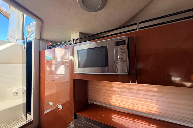 Slide: The Image of Interior of 2012 Sea Ray 310 Sundancer with microwave and wooden cabinetry. - 56