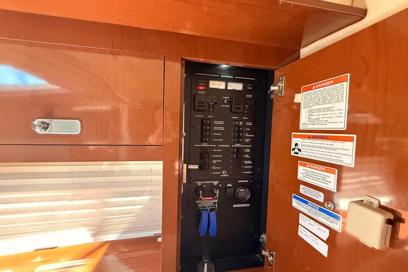 Slide: The Image of Electrical panel inside 2012 Sea Ray 310 Sundancer boat, featuring control switches and safety warnings. - 58