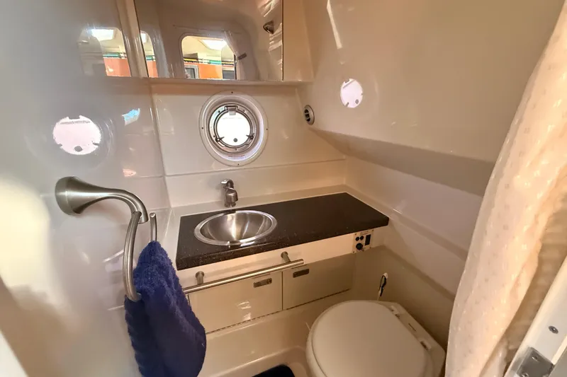 Slide: The Image of 2012 Sea Ray 310 Sundancer bathroom with sink, toilet, and porthole window. - 60