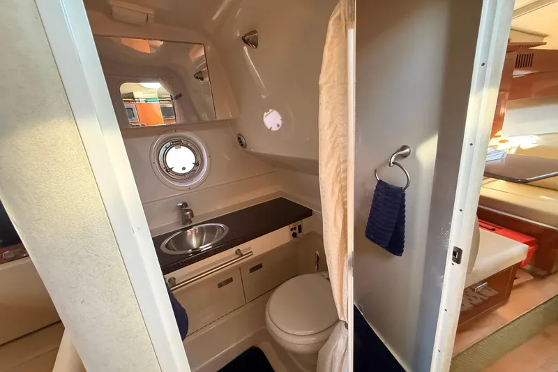 Slide: The Image of 2012 Sea Ray 310 Sundancer bathroom with sink, toilet, and porthole window. - 62