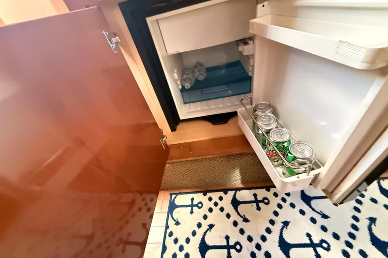 Slide: The Image of Mini fridge inside 2012 Sea Ray 310 Sundancer yacht with drinks and nautical-themed rug. - 68