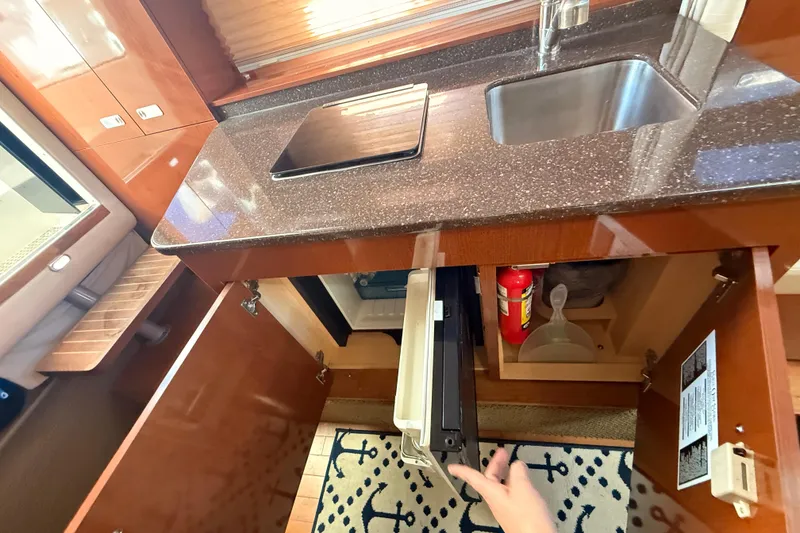 Slide: The Image of 2012 Sea Ray 310 Sundancer kitchen with sink, stove, and storage cabinets. - 70