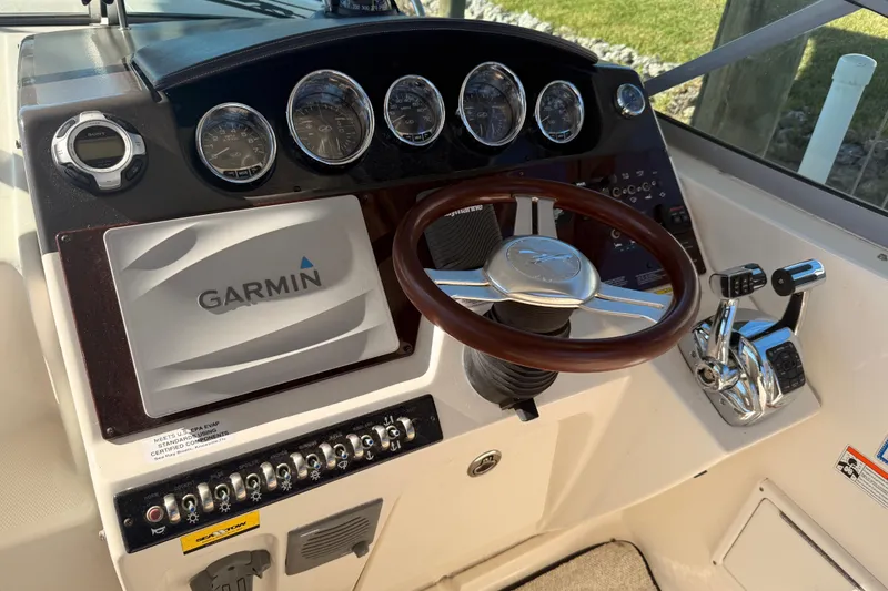 Slide: The Image of 2012 Sea Ray 310 Sundancer helm with Garmin navigation and wood-accented steering wheel. - 84