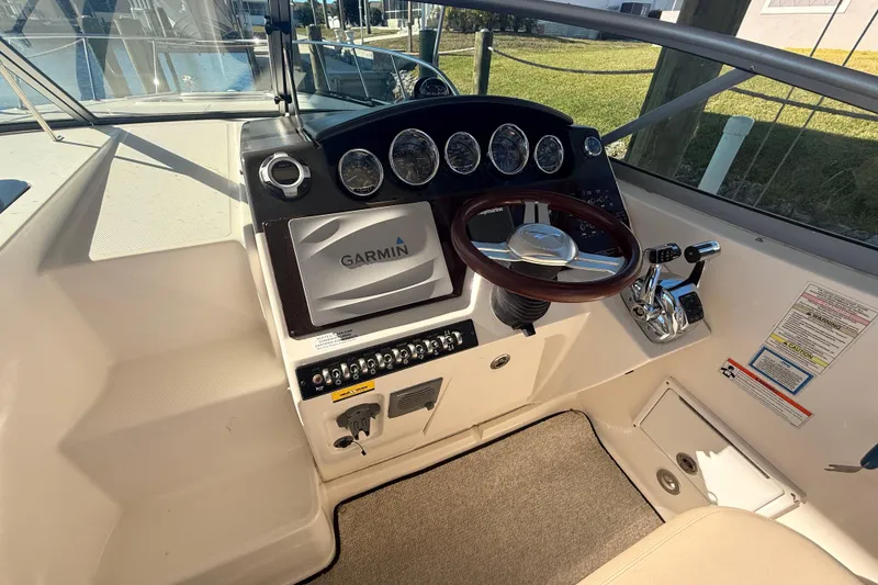 Slide: The Image of 2012 Sea Ray 310 Sundancer helm with Garmin navigation and wood steering wheel. - 85