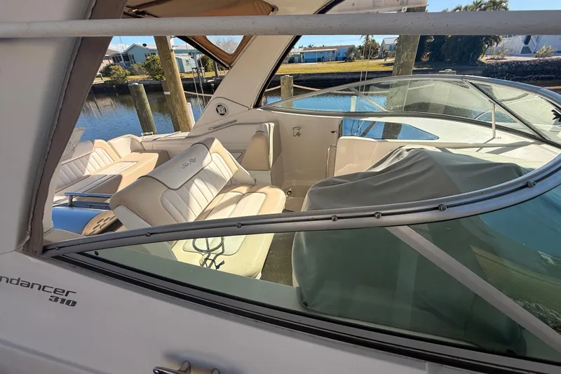 Slide: The Image of 2012 Sea Ray 310 Sundancer boat interior with beige seating and waterfront view. - 88
