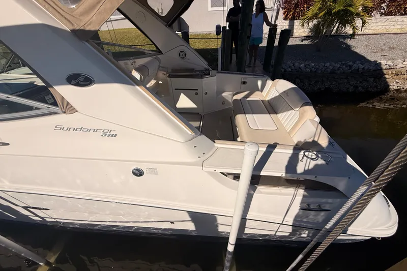 Slide: The Image of 2012 Sea Ray 310 Sundancer boat docked, featuring sleek design and comfortable seating. - 90