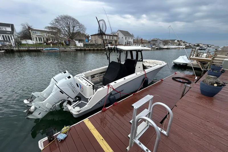 Slide: The Image of 2024 Stingray 273 CC boat docked by waterfront homes under cloudy skies. - 2