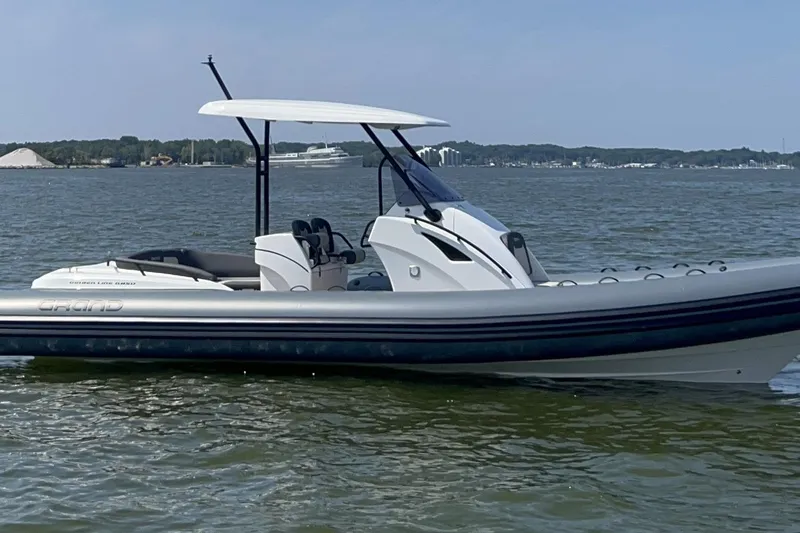 Slide: The Image of 2025 Grand Inflatables G850 boat on calm water, featuring sleek design and modern canopy. - 1