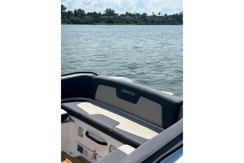 Slide: The Image of 2025 Grand Inflatables G850 boat interior with cushioned seating, overlooking a serene lake. - 9