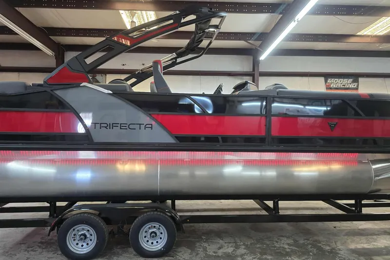 Slide: The Image of 2026 Trifecta SS 25RF pontoon boat in a showroom, featuring sleek red and black design. - 3