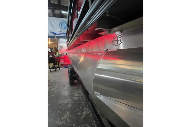 Slide: The Image of 2026 Trifecta SS 25RF pontoon boat with sleek aluminum design in a workshop setting. - 7