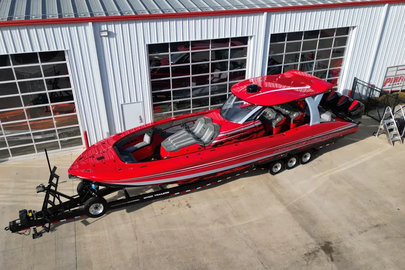 Slide: The Image of Red 2020 MTI 42V speedboat on trailer, parked outside a garage with glass doors. - 1