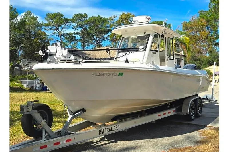 Slide: The Image of 2014 Everglades 295 Pilot boat on trailer, parked outdoors with trees in background. - 1