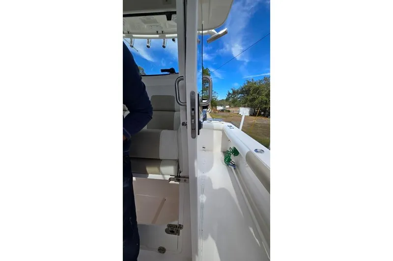 Slide: The Image of 2014 Everglades 295 Pilot boat interior with seating and open door, under clear blue sky. - 40