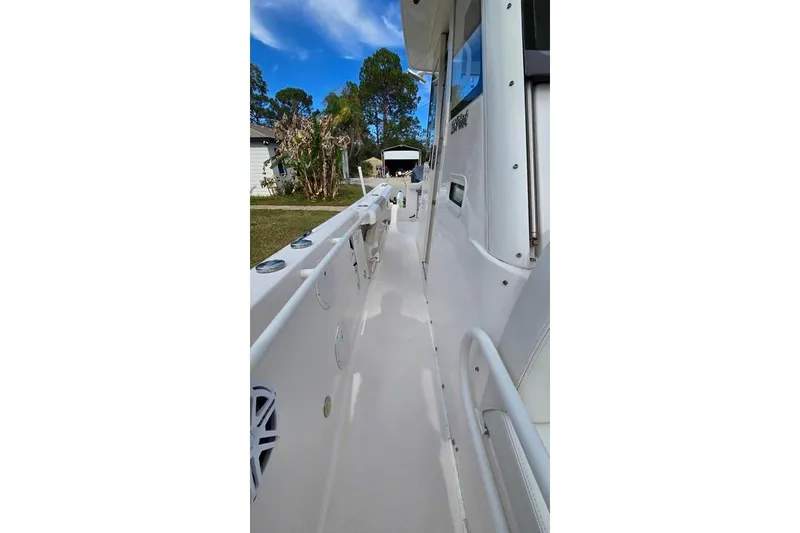 Slide: The Image of 2014 Everglades 295 Pilot boat side view, showcasing sleek white design and outdoor setting. - 52