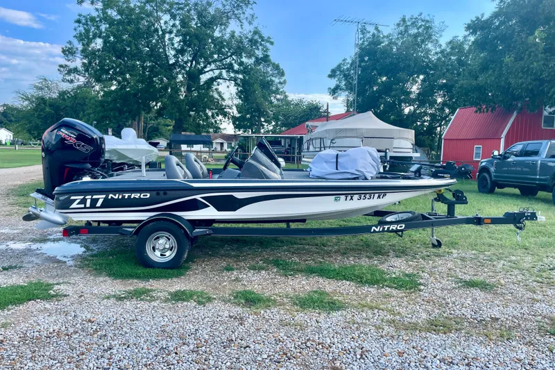 The Image of 2021 Nitro Z17 boat on trailer, parked outdoors near red barn and trees. - 1