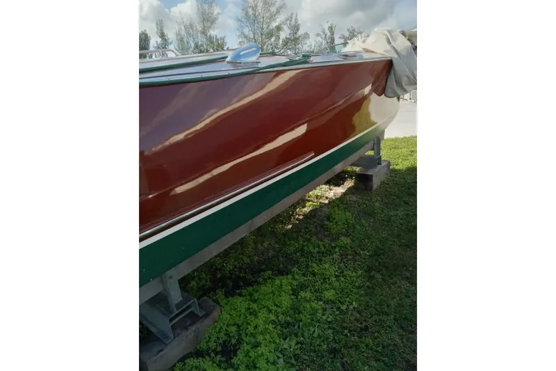 Slide: The Image of 1997 Hacker-Craft 26' Runabout boat on grass, showcasing polished wooden hull. - 15