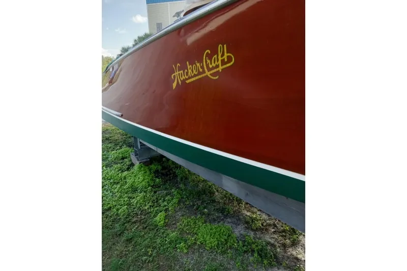 Slide: The Image of 1997 Hacker-Craft 26' Runabout boat with wooden finish and logo, displayed outdoors. - 47