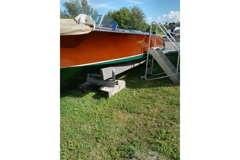 Slide: The Image of 1997 Hacker-Craft 26' Runabout on grass, supported by blocks, with a metal ladder. - 48