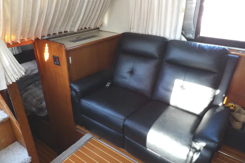 Slide: The Image of Interior of 1992 Carver 28 Aft Cabin Yacht with black leather sofa and wood paneling. - 18