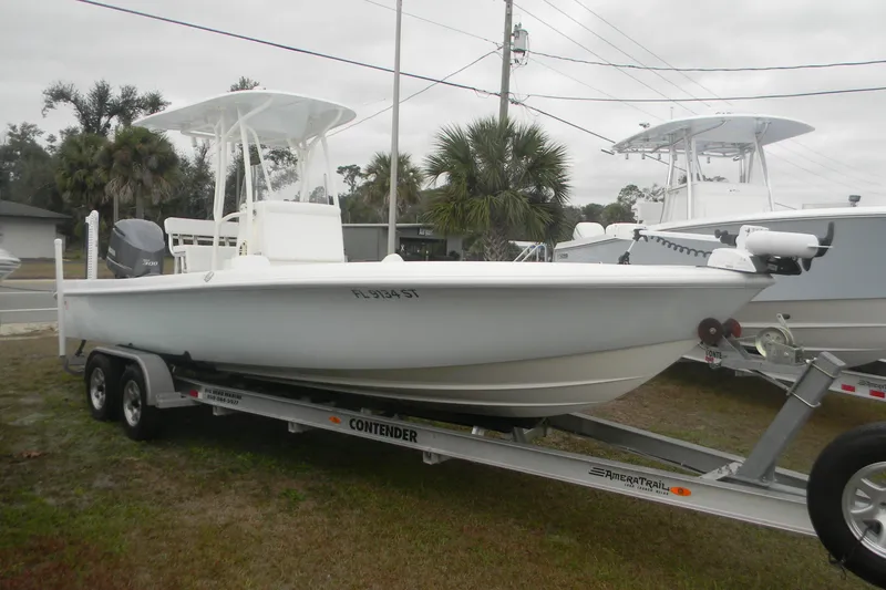 Slide: The Image of 2020 Contender 25 Bay boat on trailer, parked outdoors with palm trees in background. - 1