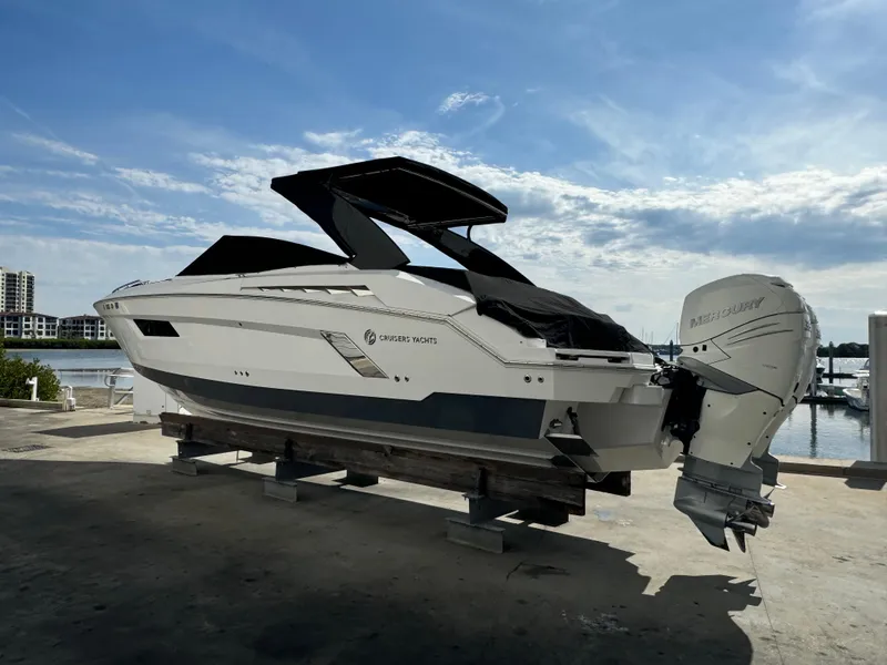 Slide: The Image of 2019 Cruisers Yachts 338 Outboard on display by the waterfront under a clear sky. - 2