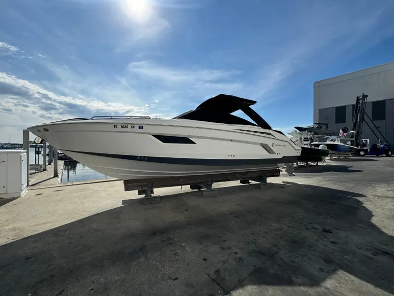The Image of 2019 Cruisers Yachts 338 Outboard on dry dock under a clear blue sky. - 0