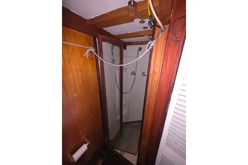 Slide: The Image of Wood-paneled shower area in a 2006 Glen-L 44 boat, featuring a glass door and showerhead. - 18