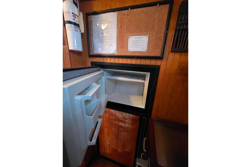 Slide: The Image of Interior of a 2006 Glen-L 44 boat with an open refrigerator and wooden paneling. - 33