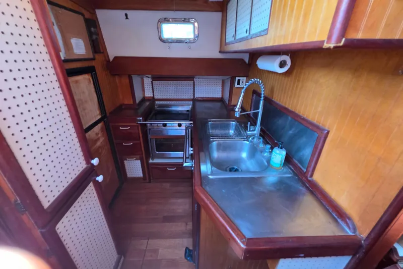 Slide: The Image of 2006 Glen-L 44 boat kitchen with wooden cabinetry, stainless steel sink, and compact stove. - 34