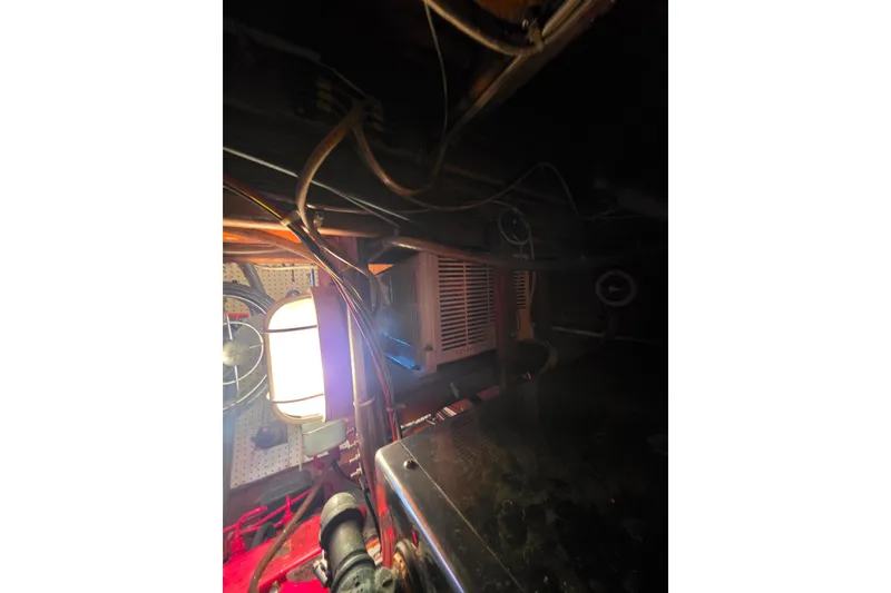 Slide: The Image of Dimly lit engine room of a 2006 Glen-L 44 boat with visible wiring and equipment. - 72