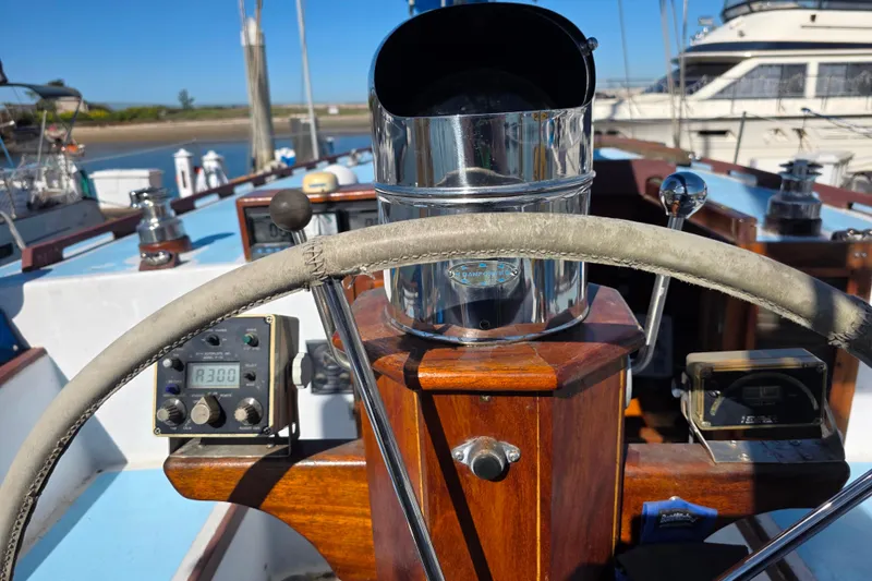 Slide: The Image of Steering wheel and controls of a 2006 Glen-L 44 boat, featuring wooden and chrome details. - 98