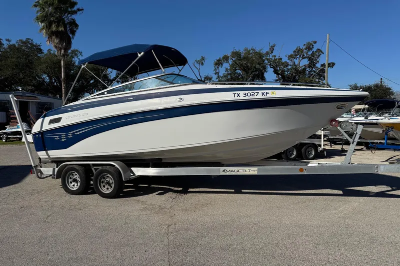The Image of 2005 Crownline 236 LS boat on trailer, parked outdoors under clear blue sky. - 1