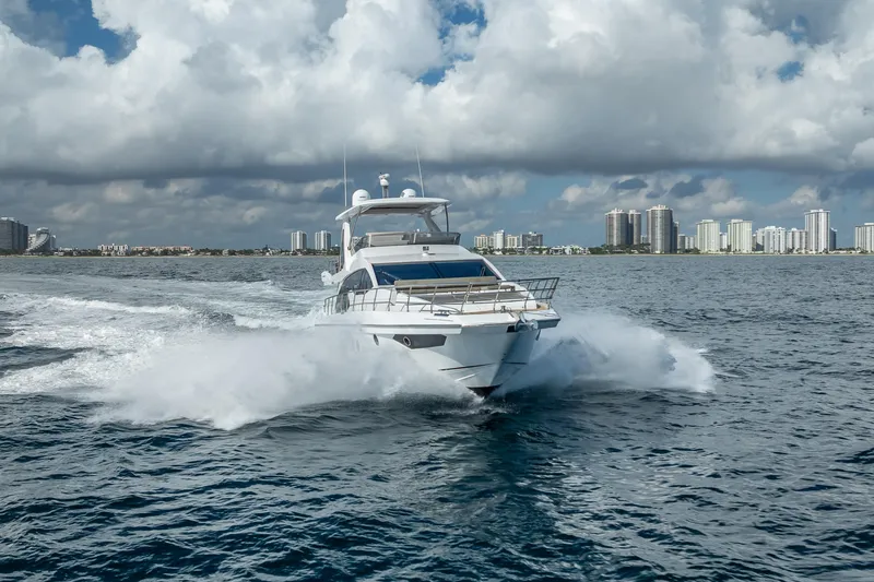 Slide: The Image of 2019 Azimut 66 yacht cruising on open water with city skyline backdrop. - 35
