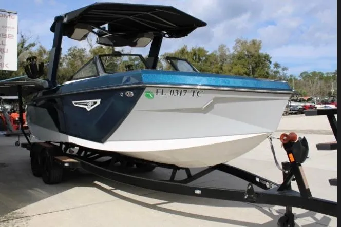 The Image of 2022 Nautique Super Air Nautique S23 boat on trailer, blue and white design. - 1