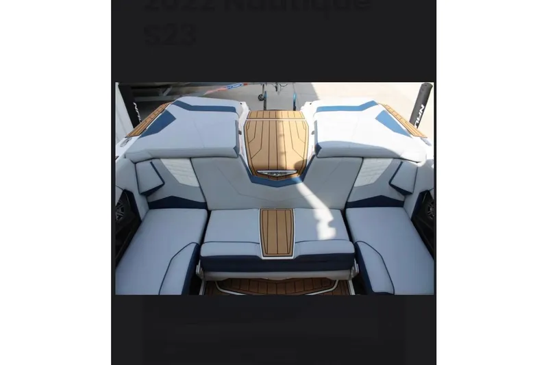 Slide: The Image of 2022 Nautique Super Air Nautique S23 boat interior with stylish seating and wood accents. - 12