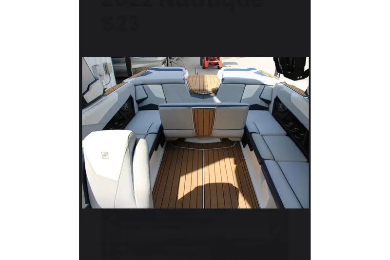 Slide: The Image of 2022 Nautique Super Air Nautique S23 interior with luxurious seating and teak flooring. - 13
