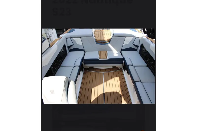 Slide: The Image of 2022 Nautique Super Air Nautique S23 interior with luxurious seating and teak flooring. - 14